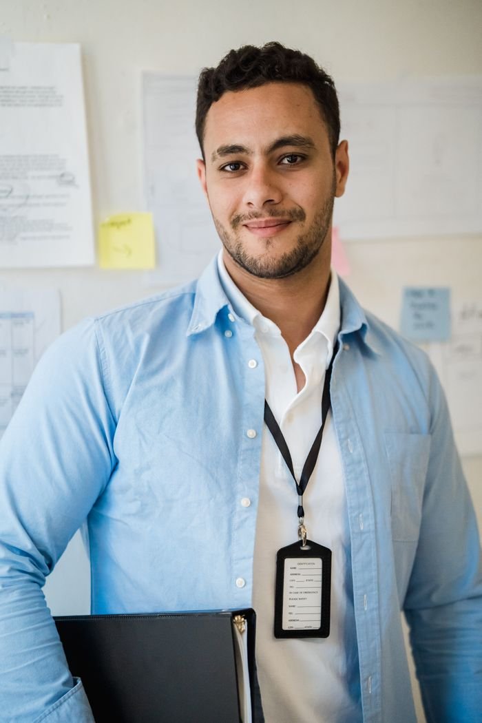 Portrait of a confident man wearing a blue shirt in an office environment holding a folder.